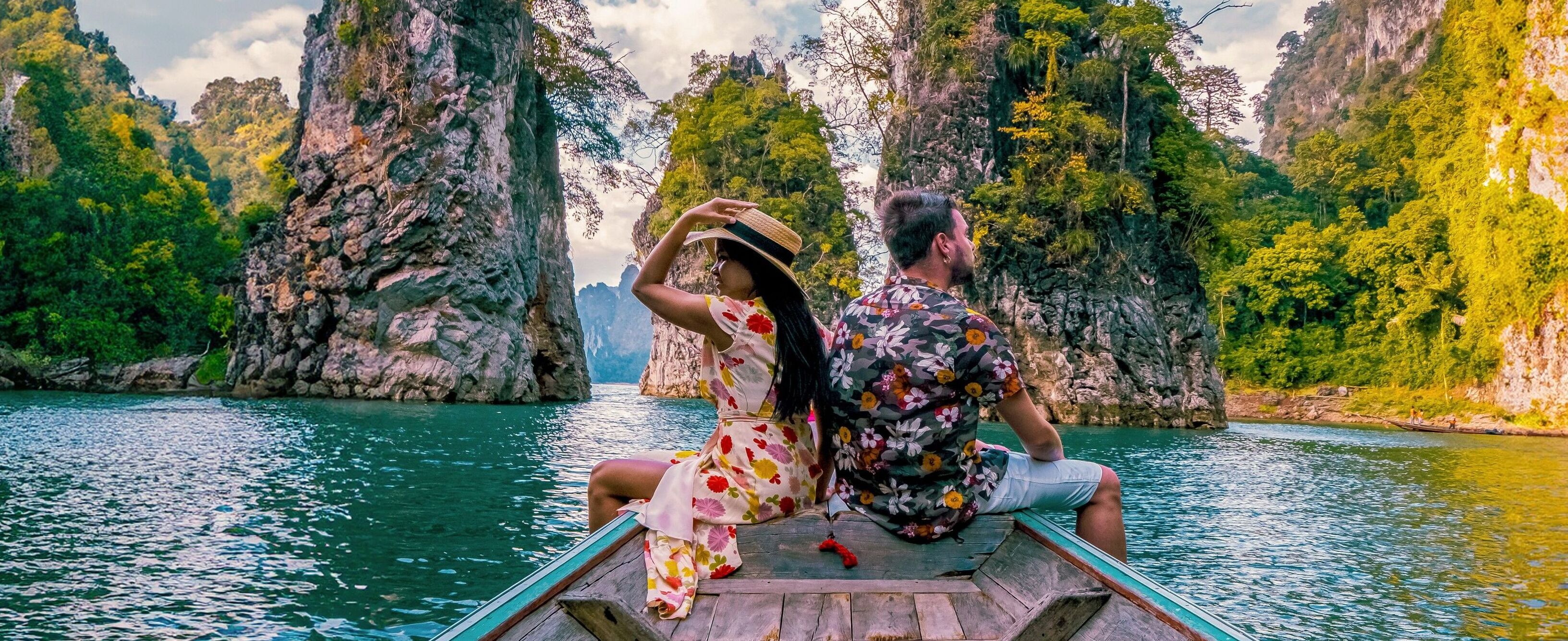 a couple traveling by longtail boat exploring epic limestone cliffs in a huge lake in Khao Sok National Park, Chiew Lan Lake, Thailand Surat Thani, men and woman in front of longtail boat